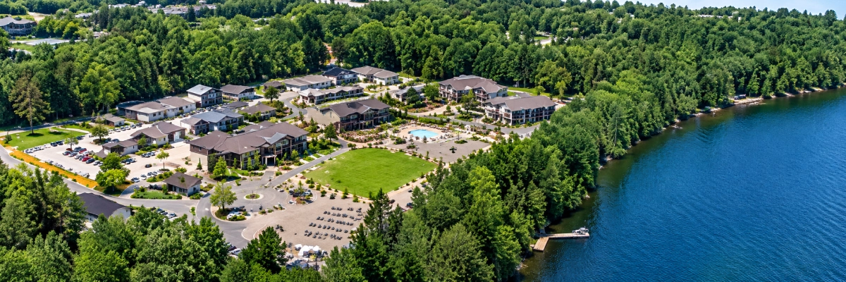 Aerial view of a lake surrounded by trees, with a resort in the background
